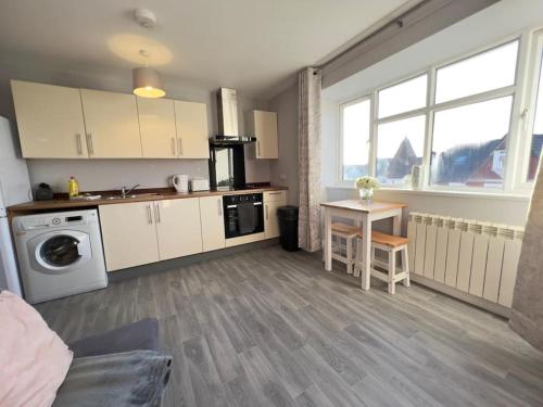 uma cozinha com armários brancos, uma mesa e um fogão em Princes Court, Sea Road em Bournemouth