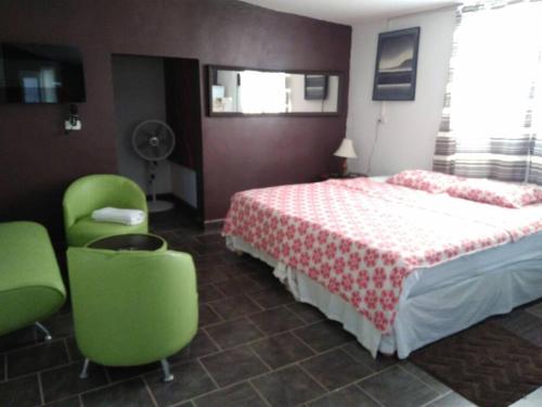 a bedroom with a bed and two green chairs at Cozy apartment in an Ecotourism El Tascate Rancho in Cuauhtémoc