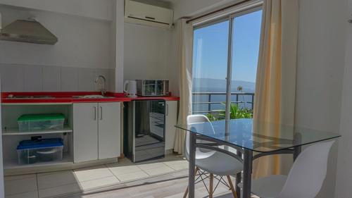 a kitchen with a glass table and a balcony at Dei Templi Apart Hotel in Viña del Mar
