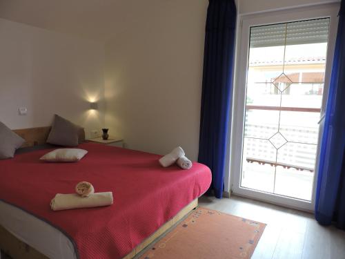 a bedroom with a red bed and a large window at Apartman IV ( 2 + 2 ) in Vodnjan