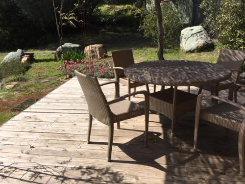 un tavolo e sedie seduti su un patio in legno di La rose bleue (2) a Olmeto