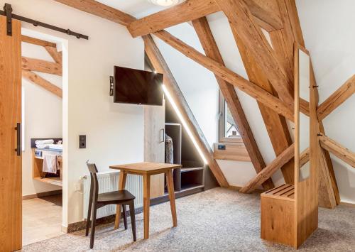 Cette chambre dispose de plafonds en bois, d'une table et d'une chaise. dans l'établissement Zum Alten Fritz, à Weigendorf
