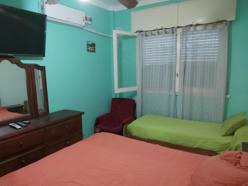 a bedroom with two beds and a mirror and a television at Chapadmalal Casas La Bella in Colonia Chapadmalal