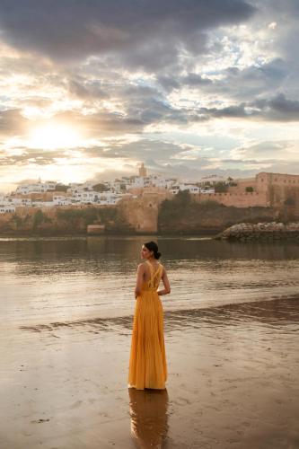 a woman in a yellow dress standing in the water at Fairmont La Marina Rabat Sale Hotel in Rabat