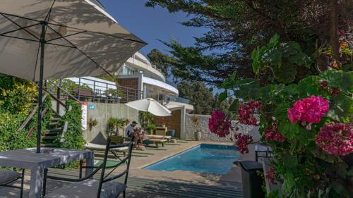 a swimming pool with a table and an umbrella and flowers at Dei Templi Apart Hotel in Viña del Mar