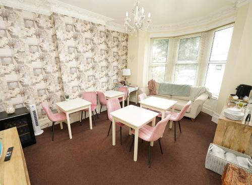 a dining room with tables and pink chairs at The Rosedene in Llandudno