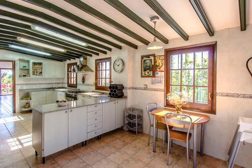 a kitchen with white cabinets and a table with chairs at Catalunya Casas Nature and Tranquility for 24 pax - 30km to beach in Sant Pere de Vilamajor