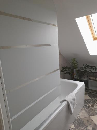 een badkamer met een wit bad en een dakraam bij Chez Marie et Hugo in Crépy-en-Valois