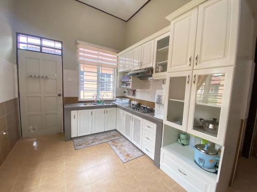 une grande cuisine avec des armoires blanches et une fenêtre dans l'établissement Homestay Affan03 Gong Badak Dekat UNISZA & 500 meter dari Pantai, à Kampong Tanjong Gelam
