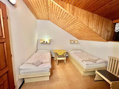 2 camas en una habitación con techo de madera en Penzión Hrubjak, en Oravská Polhora