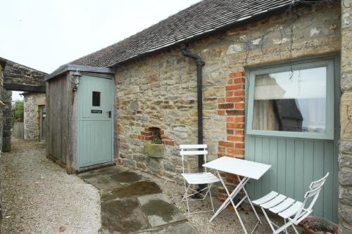 a table and chairs sitting outside of a brick building at Dumble Cottage in Ashbourne