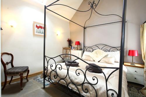 a black canopy bed in a bedroom with a chair at Dumble Cottage in Ashbourne