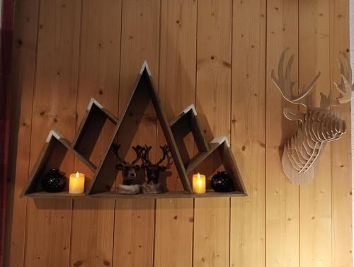 a shelf with candles and antlers on a wall at Appart. lumineux à St-Sorlin d'Arves (Sybelles) in Saint-Sorlin-dʼArves