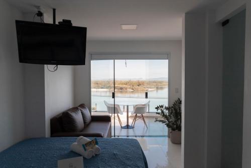 a bedroom with a bed and a table and a view of a room at Suítes Luxo Marambaia- Epic House in Rio de Janeiro