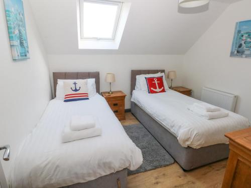 a bedroom with two beds and a window at The Boathouse in Tenby