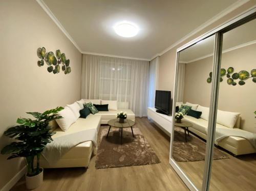 uma sala de estar com um sofá e uma televisão em Liget Hévíz Apartman em Hévíz