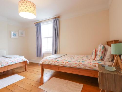 a bedroom with two beds and a window at Pepperpot Cottage in Bude