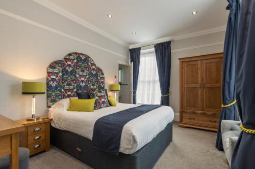 a bedroom with a large bed with a large headboard at Hotel Plas Hyfryd in Narberth