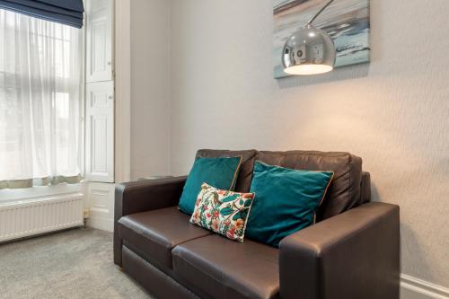 a brown couch with blue pillows in a living room at Hotel Plas Hyfryd in Narberth