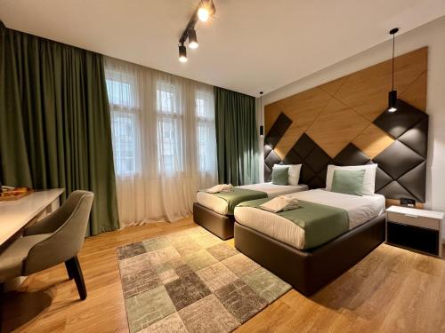 a bedroom with two beds and a table and a desk at Capital Hotel Garni in Belgrade