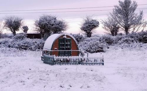 a small house in a field covered in snow at Lovely Glamping Dream Pod in St Austell Cornwall in St Austell