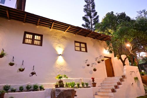 a white house with potted plants in front of it at Achalaa Resort in Kolhapur