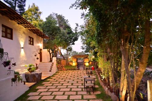 einen Garten mit einem Steinweg und Bäumen in der Unterkunft Achalaa Resort in Kolhapur