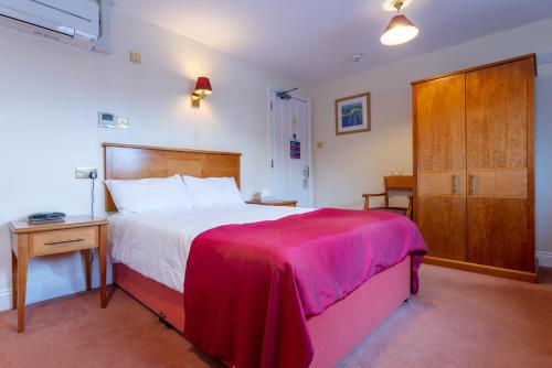 um quarto com uma cama grande e um armário de madeira em The Evenhill em Canterbury