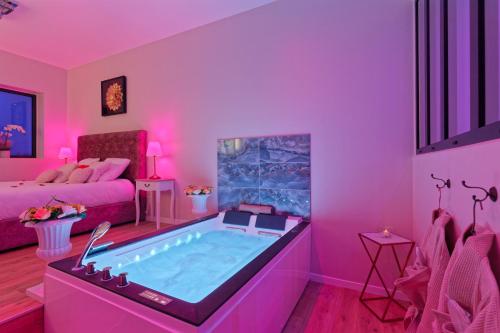 - un salon avec un bain à remous dans une pièce rose dans l'établissement Romance Spa Nuit D'amour, au Havre