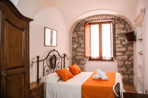 una camera da letto con un letto con cuscini arancioni e una finestra di S’ammentu house a Bosa