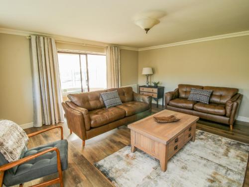 a living room with leather couches and a coffee table at The Marshes in Welshpool
