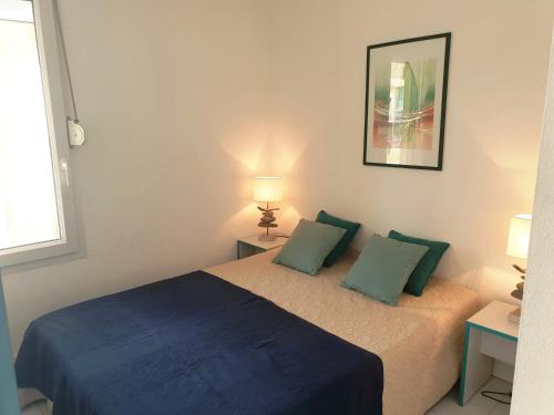 a bedroom with a bed with two green pillows at SAVANNA BEACH I Joli T2 piscine vue mer Cap d'Agde in Cap d'Agde