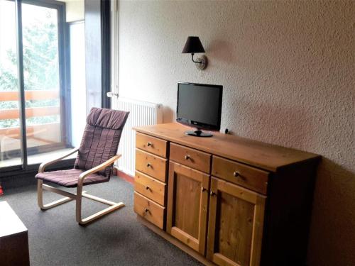 Cette chambre dispose d'une télévision sur une commode en bois avec une chaise. dans l'établissement Charmant 2 pièces, centre, 5 pers. avec balcon, quartier La Croisette, Les Belleville - FR-1-574-9, aux Menuires