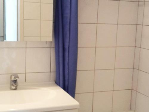 La salle de bains est pourvue d'un rideau de douche bleu à côté d'un lavabo. dans l'établissement Appartement 32m², centre Croisette, 5 couchages, Wifi, animaux admis - FR-1-574-25, aux Menuires