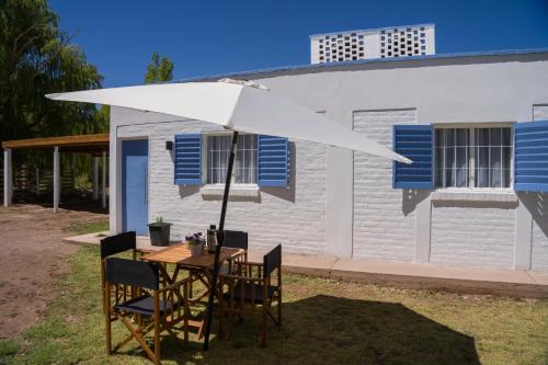 a table and chairs under an umbrella in front of a building at Complejo Willy Pampa in Barreal
