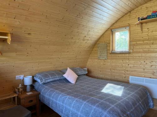 ein Schlafzimmer mit einem Bett in einer Holzhütte in der Unterkunft Cosy Cabins at Westfield Farm in Yarmouth