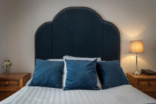 a bed with a black head board and blue pillows at Hotel Plas Hyfryd in Narberth
