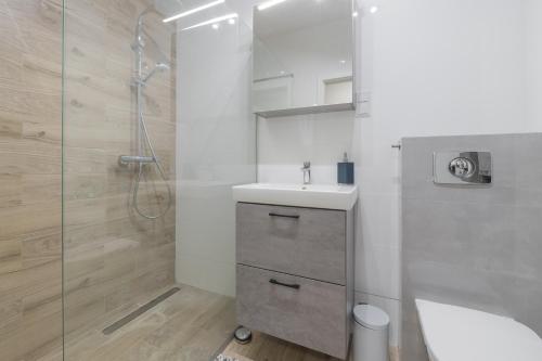 a white bathroom with a sink and a shower at Apartament Kapitalny in Gdańsk