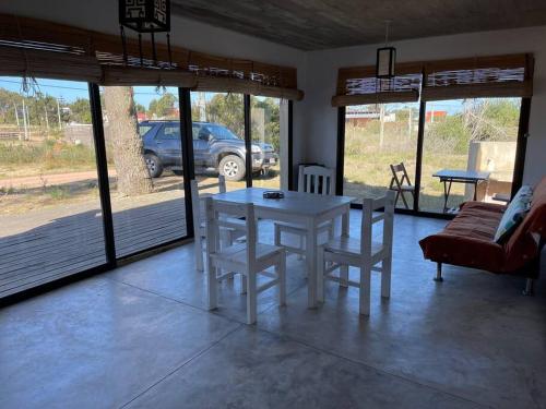 una mesa blanca y sillas en una sala de estar con coche en La Pasionaria casa cerca del mar, en Punta del Diablo