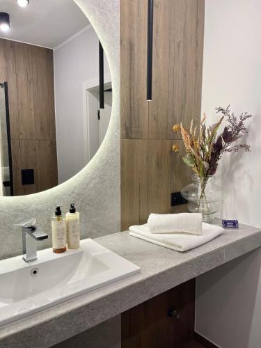W łazience znajduje się umywalka i lustro. w obiekcie ApartamentCentrum-CHARLOTTE -PARKING- w mieście Bolesławiec