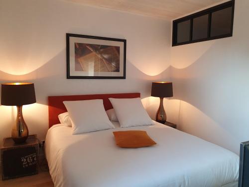 een slaapkamer met een wit bed en 2 lampen bij La P'tite Maison in Carlux