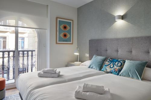 a bedroom with a large bed and a balcony at The Rentals Collection - Olabar II in San Sebastián