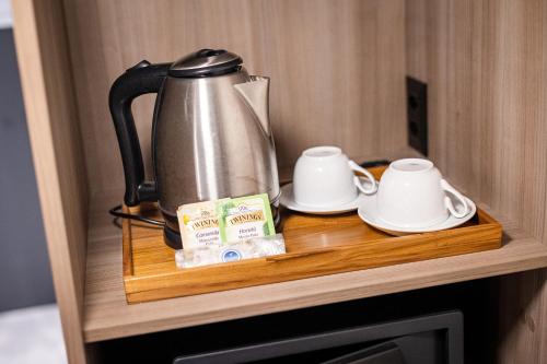 a coffee pot and two cups on a wooden shelf at Novotel BH Savassi in Belo Horizonte