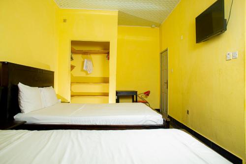 a bedroom with two beds and a tv on a yellow wall at Jennabwa Lodge and Restaurant in Freetown