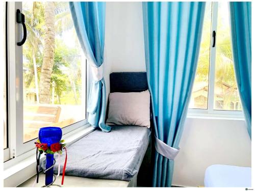 a small bed in a window with blue curtains at Ayona Beach Villa in Katuneriya