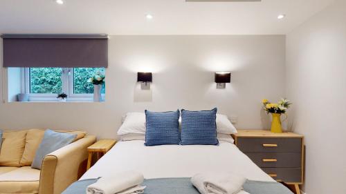 - une chambre avec un lit doté d'oreillers bleus et d'un canapé dans l'établissement Wimbledon Studios, à Londres