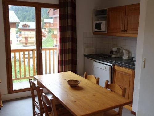 een keuken met een houten tafel met stoelen en een raam bij Appartement Valfréjus, 3 pièces, 6 personnes - FR-1-265-182 in Valfréjus