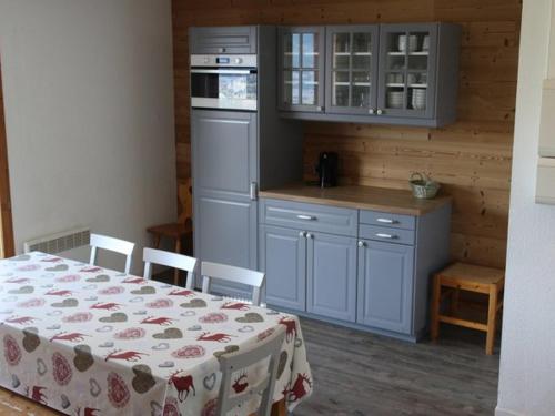 een keuken met blauwe kasten en een tafel en stoelen bij Appartement Valfréjus, 3 pièces, 10 personnes - FR-1-265-191 in Valfréjus