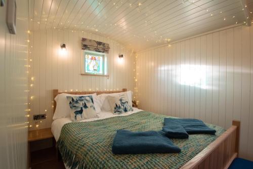um quarto com uma cama com duas toalhas azuis em Luxury Twin Shepherds Hut - Cosy & Romantic em Llandudno