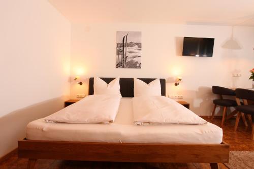 a bedroom with a bed with white sheets and pillows at Gästehaus Etschmann in Riezlern